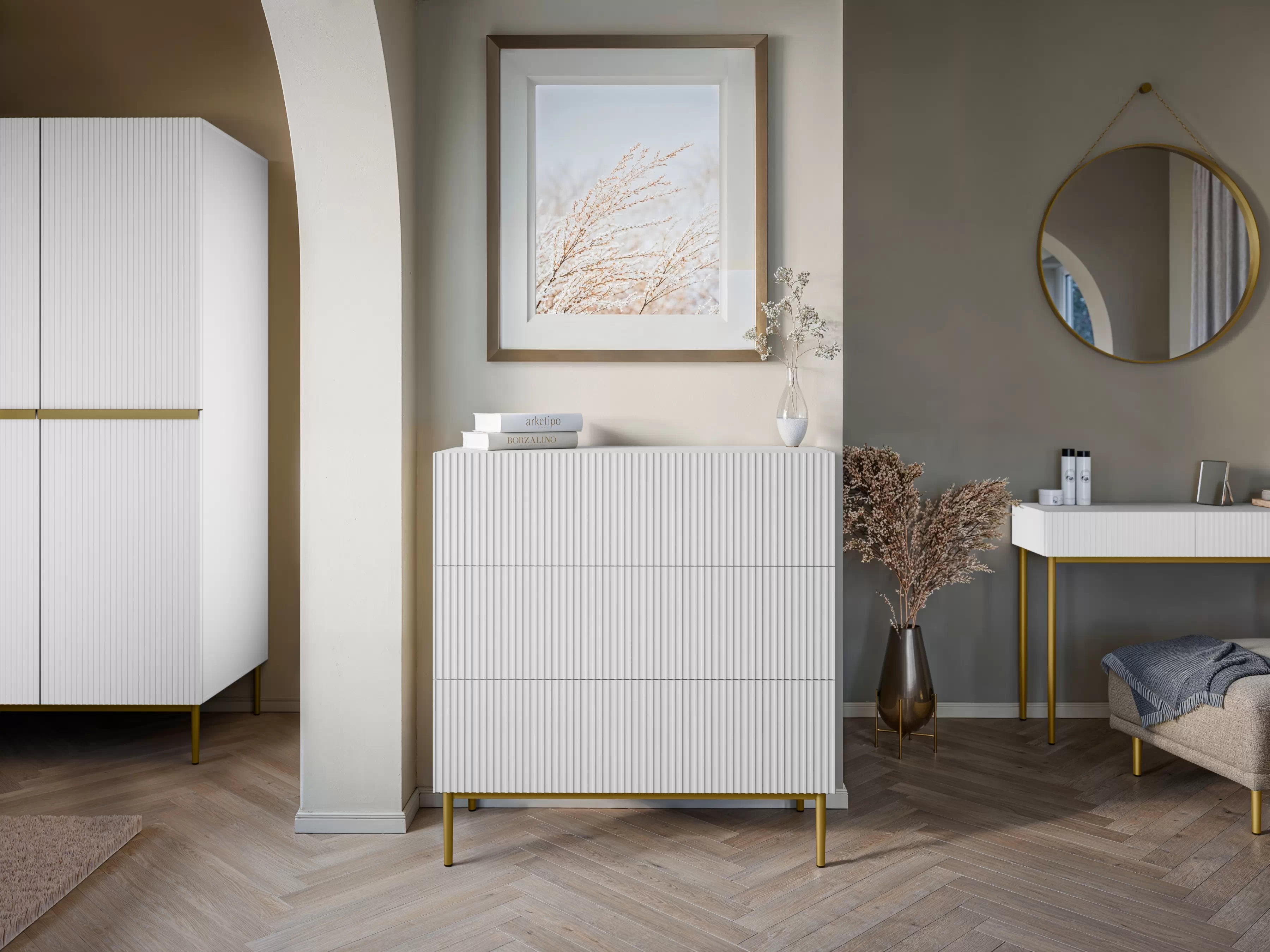 Biela komoda Nicole 100 cm so zásuvkami a ryhovaným čelom - matná biela / zlaté nožičky Komoda Nicole 100 cm so zásuvkami i ryflowanym frontem - biely mat / zlote nozki